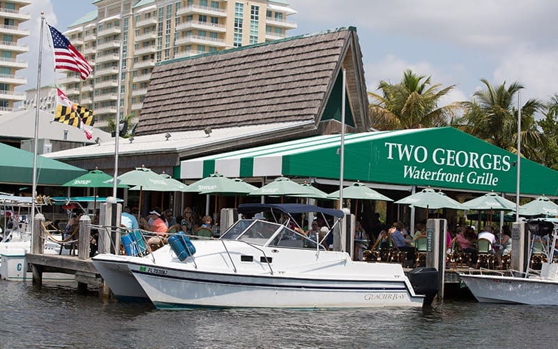 People are dinning at the Two Georges Restaurant, which is located on the water. It is a popular dinning destination for both residents and tourists.